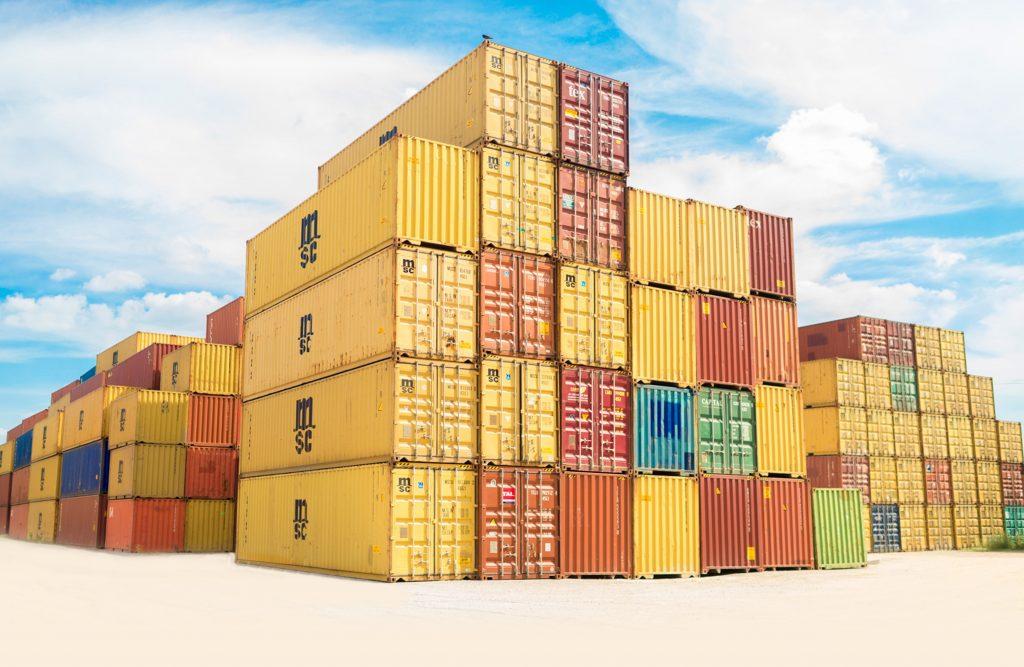 Yello cargo containers stacked up at a port with a blue sky